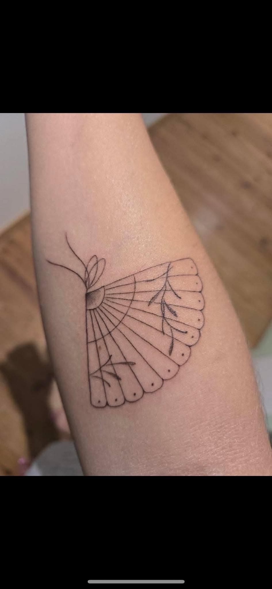 Tatouage fine line : éventail traditionnel avec branche feuillue sur l’avant-bras