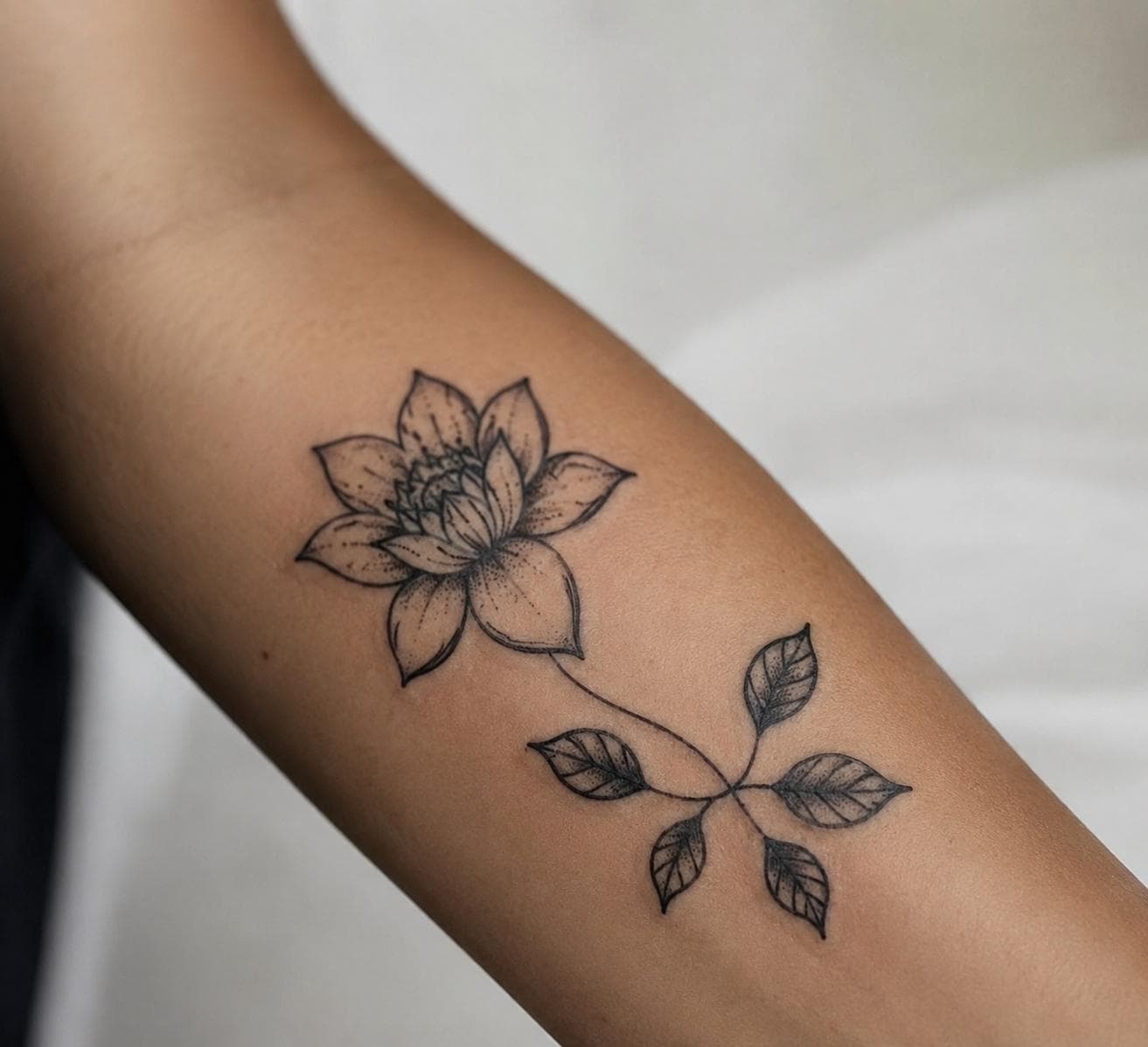 Tatouage floral fine line en cours de réalisation sur un avant-bras